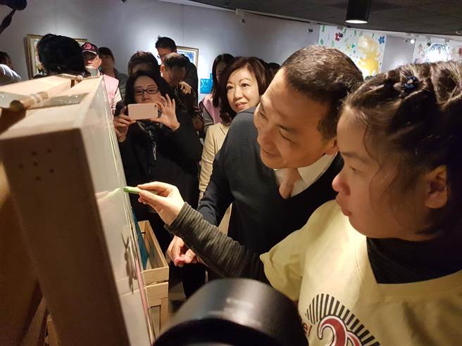 新北市文化局與台灣遲緩兒天使樂園協會共同舉辦「天使的迷宮–慢飛天使藝術展」，副市長侯友宜（左）出席與自閉兒陳妍欣（右）一起作畫。（葉書宏攝）